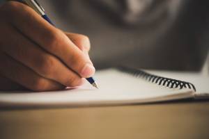 Man hand with pen writing on notebook.